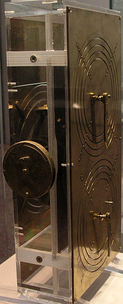Replica of the Antikythera Instrument: Based on the research of Professor Derek de Solla Price, in collaboration with the National Scientific Research Center "Demokritos" and physicist CH Karakalos who carried out the x-ray tomography of the original. This mechanism has been rebuilt to show the likely operation of the original. Price built a rectangular box of 33 cm X 17 cm X 10 cm with protective plates bearing Greek inscriptions of planets and operational information. Photo by Wikipedia user Marsyas (Creative Commons)